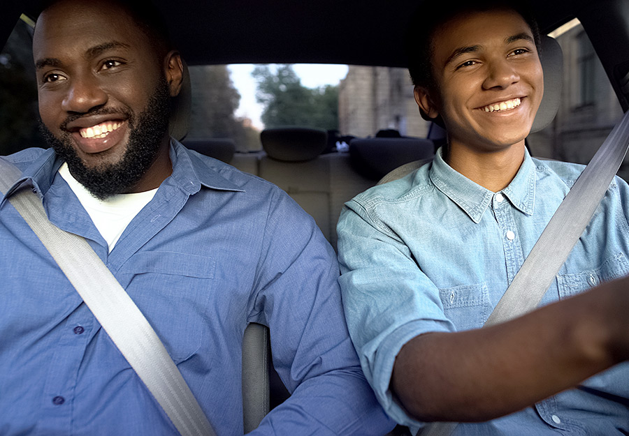 A young man confidently driving, with an adult in the passenger seat