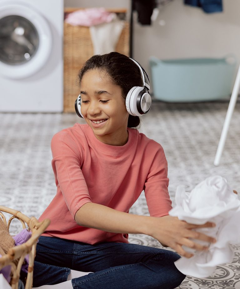 A young girl wearing headphones and sorting laundry
