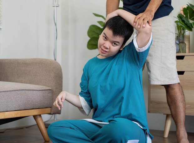 A wellness activity where a man helps a young patient with flexibility